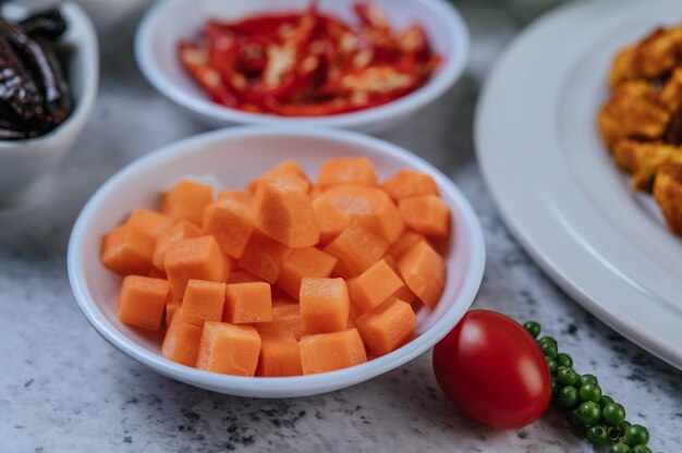Las zanahorias se cortan en cubitos en una taza con tomates y semillas frescas de pimiento.