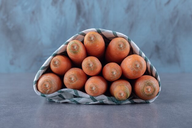 Zanahorias envueltas en una toalla, sobre la superficie de mármol.