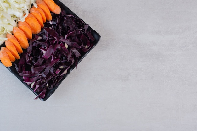 Foto gratuita zanahorias picadas, repollo rojo y blanco sobre placa negra. foto de alta calidad