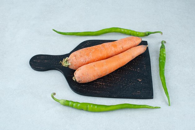 Zanahorias y pimientos maduros en tablero oscuro.