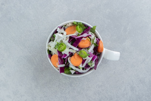 Zanahorias en rodajas, repollo, verduras, en una taza, en el mármol.