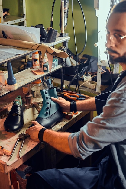 Zapatero experimentado está creando zapatos de cuero retro en su cómodo taller.