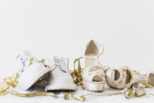 Zapatos de boda blancos y tacón alto de elegancia con serpentinas doradas sobre fondo blanco