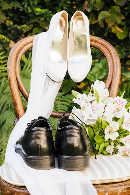 Zapatos de boda; bufanda y ramo de flores en silla de madera