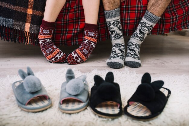 Zapatos de casa acogedores en el piso cerca de las piernas humanas