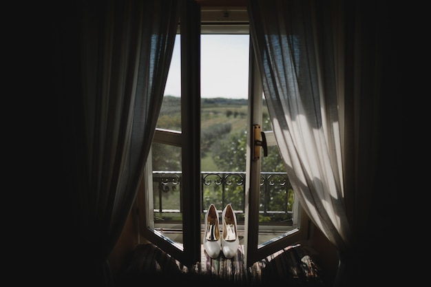 Los zapatos de novia se colocan en el alféizar de la ventana con una gran vista detrás de él