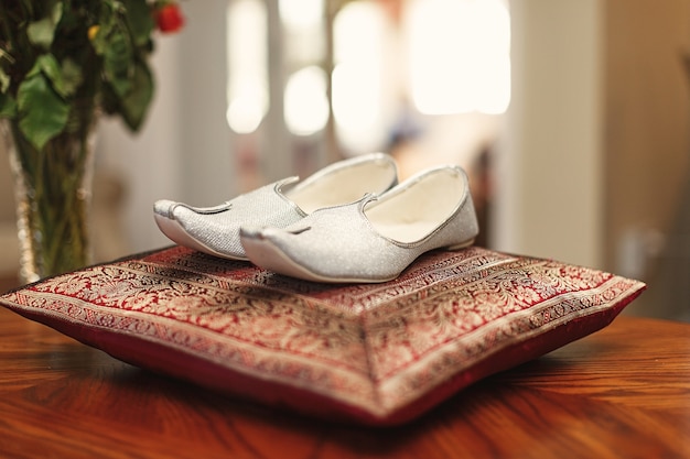 Foto gratuita zapatos de plata del novio indio de pie en la almohada roja