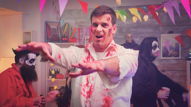 Zombie aterrador y peligroso en la fiesta de halloween divirtiéndose y bailando junto a sus amigos disfrazados