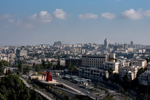 Zona urbana rodeada de edificios verdes y carreteras bajo la luz del sol y un cielo nublado