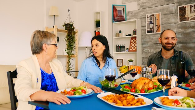 Zoom en la toma de una hermosa joven hablando con su madre de unos sesenta años en la cena familiar.