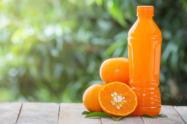 Zumo de naranja en botella y naranjas