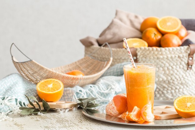 Zumo de naranja ecológico recién cultivado en el interior de la casa, con manta turquesa y cesta de frutas. Comida sana. Vitamina C