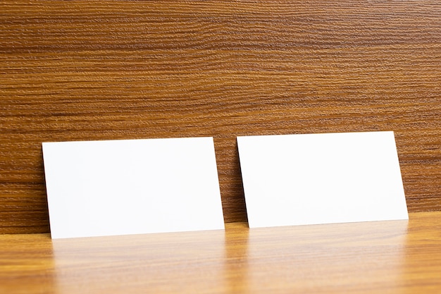 2 biglietti da visita in bianco bloccati su una scrivania in legno testurizzato, dimensioni 3,5 x 2 pollici