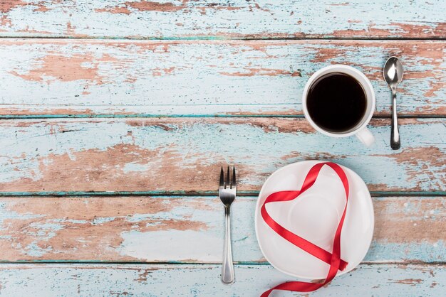 A forma di cuore dal nastro sul piatto con caffè