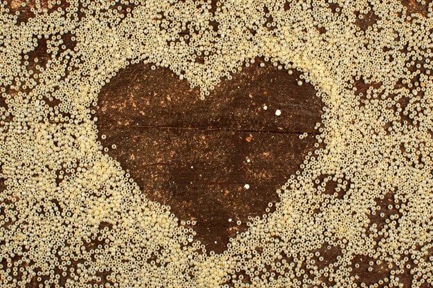 Abbottona la forma di cuore circostante gialla su un pavimento marrone rustico di legno