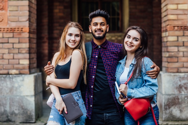 Abbracci. In piedi in Università. Buon umore. Intelligenza. Studenti felici in piedi insieme, fuori.