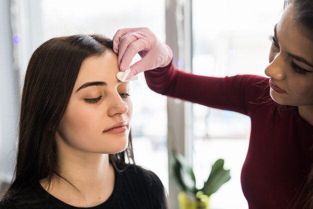 Abile visagiste che fa sopracciglia nere per una giovane donna