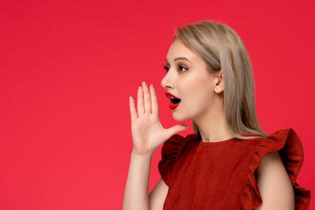 Abito rosso ragazza carina elegante di classe in abito bordeaux con rossetto rosso mani intorno alla bocca che chiama