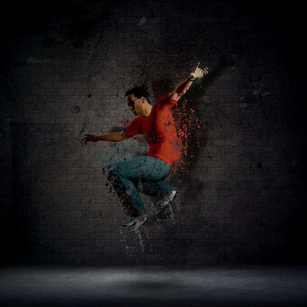 Abstract grunge uomo che balla contro un muro di mattoni scuri