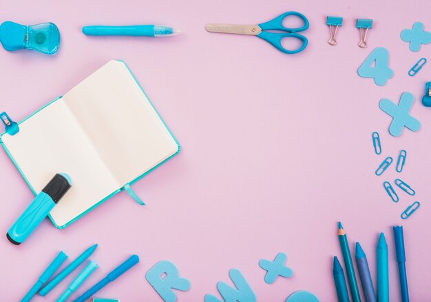 Accessori artigianali blu con diario aperto e pennarello disposti su sfondo rosa