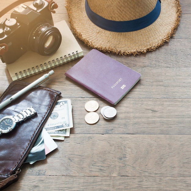 Accessori del viaggiatore, elementi essenziali di vacanza di giovane con passaporto, macchina fotografica e borsa su sfondo di legno con spazio di copia