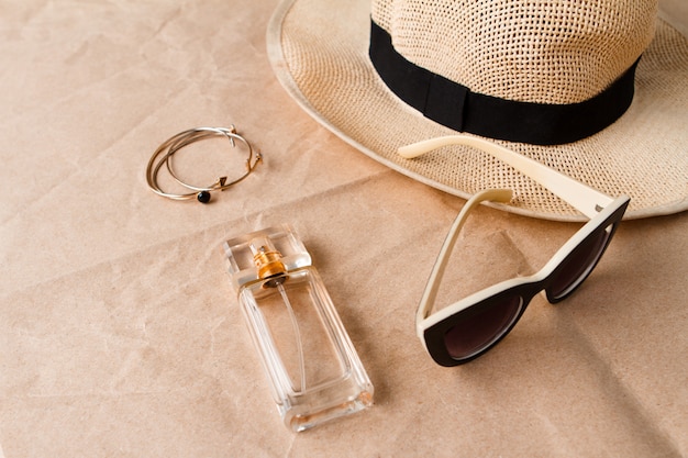 Accessori occhiali da sole profumo e cappello su superficie artigianale