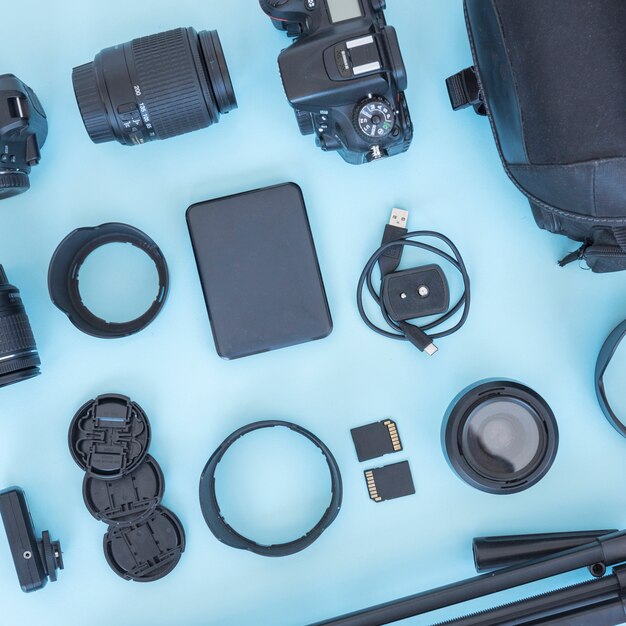 Accessori per il fotografo professionali e attrezzature disposte su sfondo blu