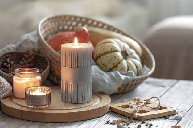 Accogliente composizione autunnale con candele accese e zucche su uno sfondo sfocato.