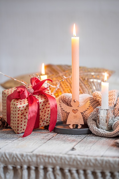 Accogliente natura morta festiva con un regalo e una candela su un tavolo di legno. Il concetto di festa.