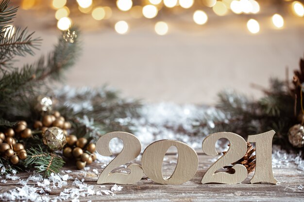 Accogliente sfondo di Natale con numeri 2021 in legno decorativi su sfondo sfocato con luci.
