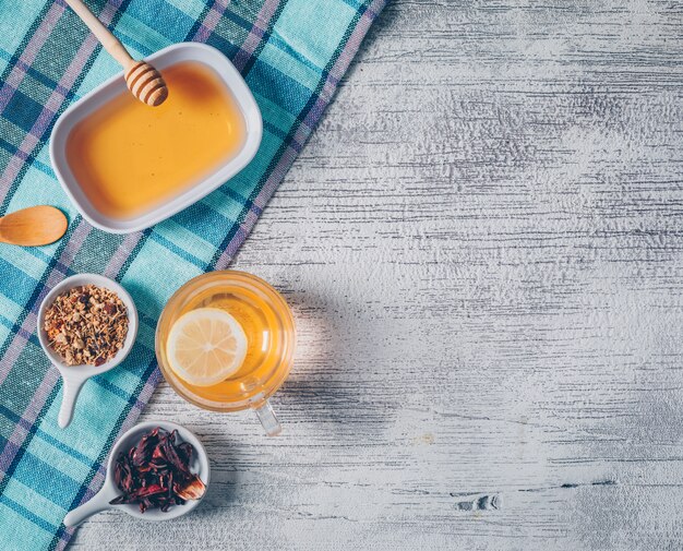 Acqua arancione di vista superiore con miele ed erbe del tè sul panno di picnic e sul fondo di legno grigio. spazio orizzontale per il testo