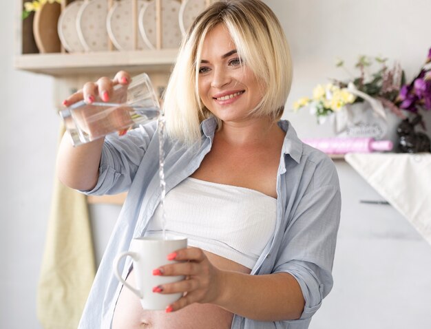 Acqua di versamento della donna incinta in un vetro