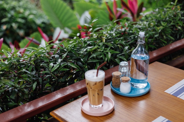 Acqua in una bottiglia di vetro latte ghiacciato su un supporto rosa sale e carta sul tavolo di legno