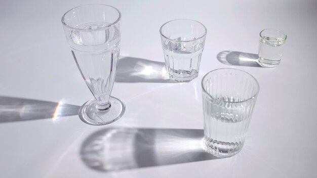 Acqua nel diverso tipo di occhiali con ombra su sfondo bianco