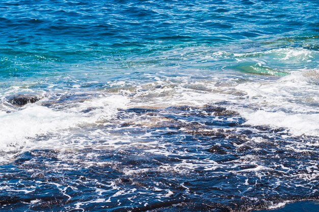 Acqua ondulata cristallina del primo piano alla spiaggia