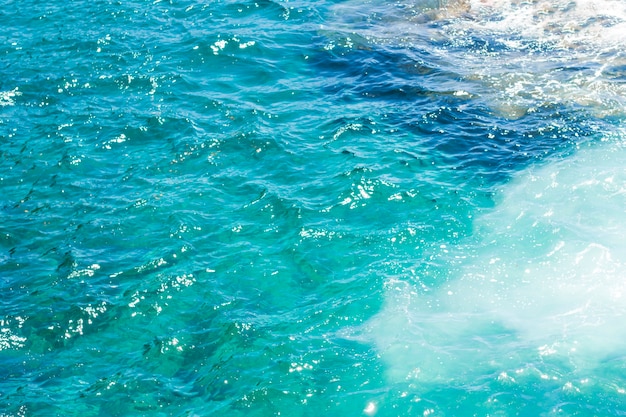 Acqua ondulata cristallina del primo piano alla spiaggia