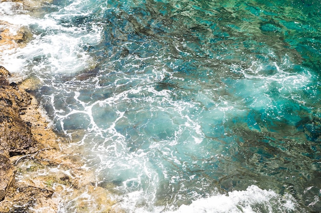 Acqua ondulata cristallina del primo piano alla spiaggia