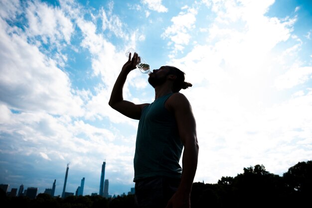 Acqua potabile del corridore con il fondo del cielo