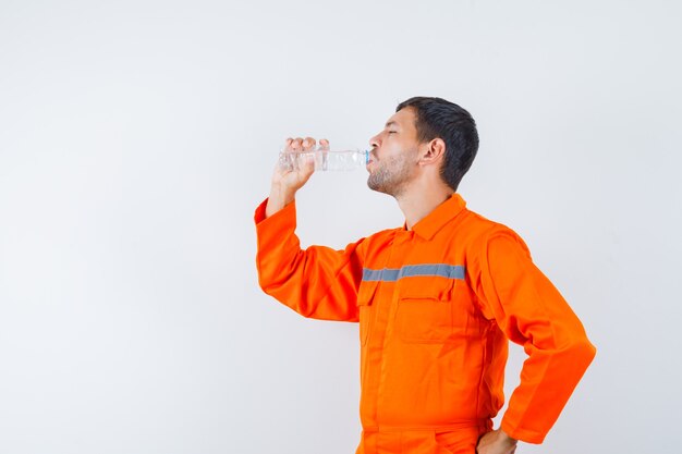 Acqua potabile dell'uomo industriale in uniforme e che sembra assetato. .