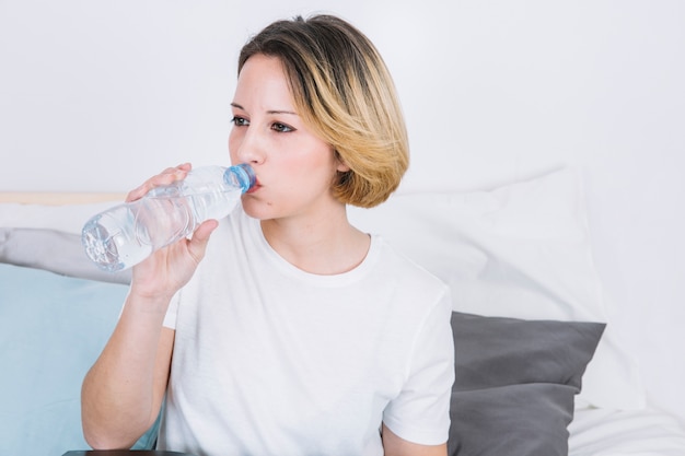 Acqua potabile della giovane donna dalla bottiglia