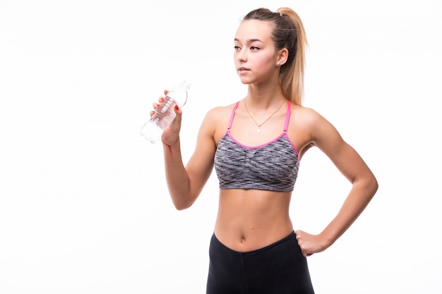 Acqua potabile della ragazza da una bottiglia transperent su un bianco