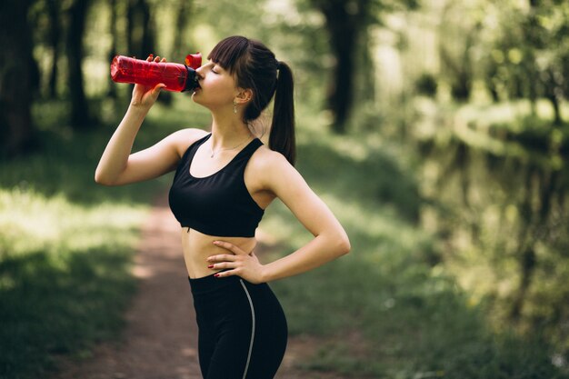 Acqua potabile della ragazza sportiva in parco