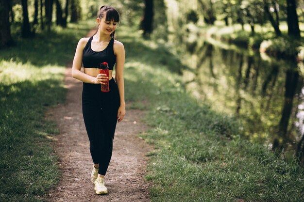 Acqua potabile della ragazza sportiva in parco