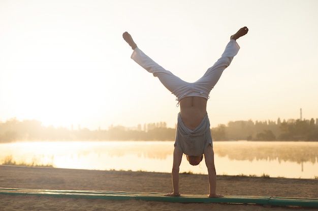 Addestramento atletico di allenamento dell'esecutore di capoeira sull'alba della spiaggia