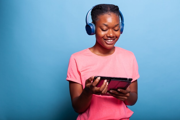 Adolescente afroamericano con le cuffie che tengono il computer tablet