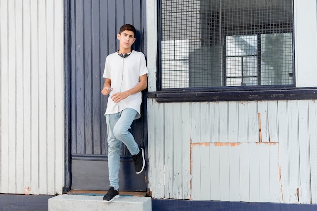 Adolescente bello che si appoggia sul raccordo ondulato del ferro che esamina macchina fotografica