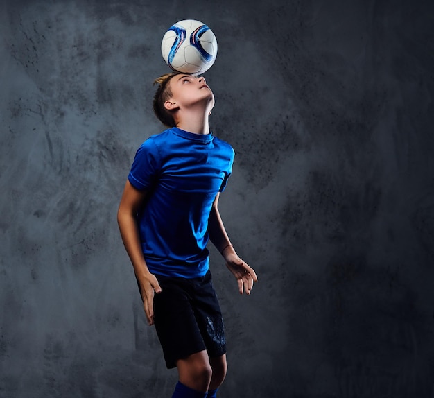 Adolescente bionda, giocatore di calcio vestito con un'uniforme blu gioca con una palla.