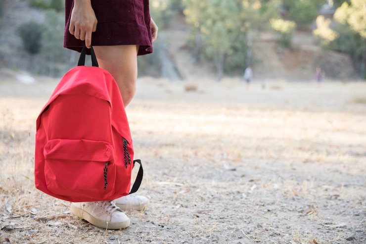 Foto gratuito adolescente che aspetta con lo zaino a disposizione nel parco