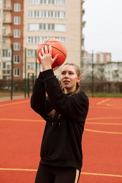 Adolescente che gioca a basket all'aperto