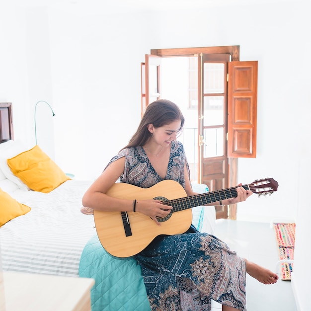 Adolescente che gioca chitarra in camera da letto